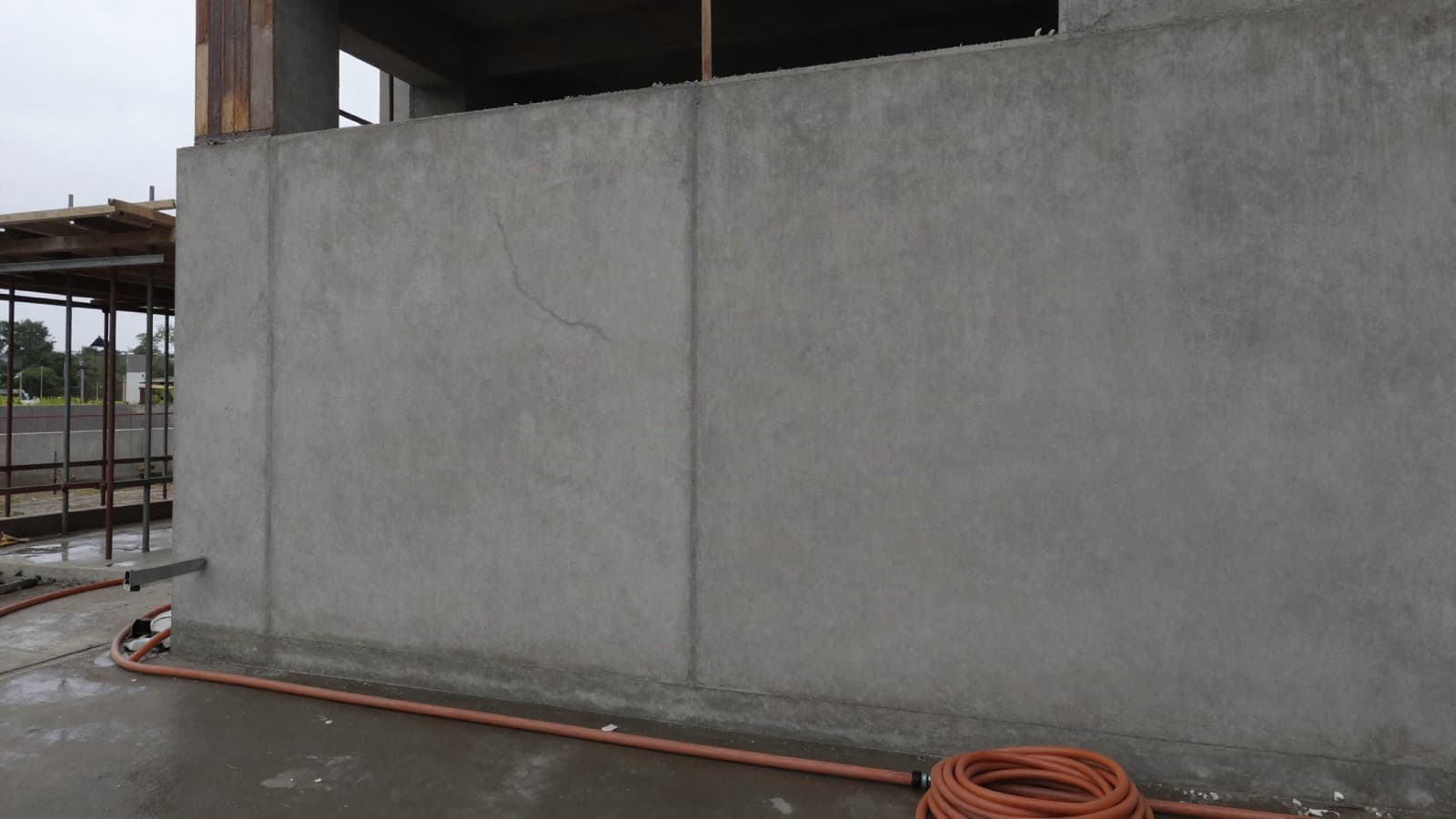 Concrete wall of an unfinished building with a hairline crack, photographed as a site record